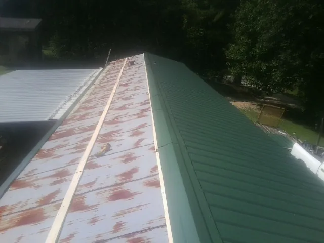 Old rusted panels beside newly installed green metal roofing — Wind Damage Roof Repair by Roofing Brothers in Wyoming